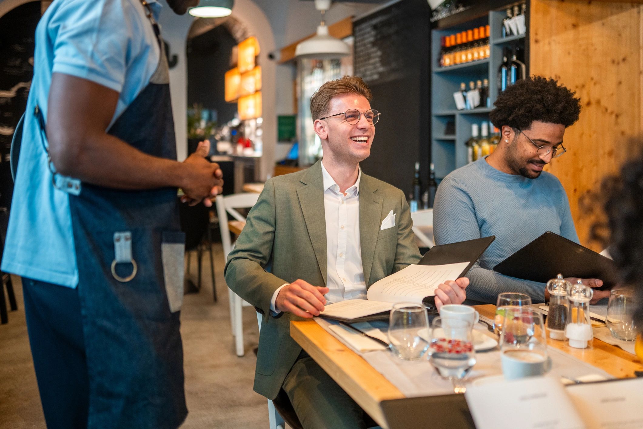 Young Adult Male Friends Discussing Menu Options in Cozy Bistro